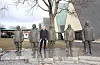 Harald Dag Jølle har skrive boka «Ytterst i verden». Her står han saman med statuane av Roald Amundsen og ekspedisjonen hans som blei dei første til å nå Sørpolen i 1911. Foto: Kjell Åsmund Sunde/ NPK
