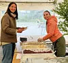 God stemning ved serveringsbordet: Guro Eriksen Røher lar seg friste av maten som Jagoda Agnieszka Tarnowska byr på under bygdefesten i Auklandshamn. Foto: Privat