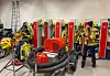 To brannfolk i garderobe med gule hjelmar og brannutstyr rundt seg.