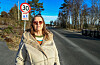 Kvinne står ved en stille boligvei med 30-sone og barn-leker-skilt.