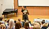 Mann i kostyme fortel frå scena til barn i eit auditorium