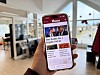 Hand som held ein mobiltelefon med ei lokalavisa Vestavind open på skjermen i eit kontorlokale.