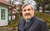 Kåre bua ute framfor kvitt hus med grøne lister og berg i bakgrunnen