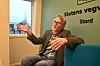 Mann sit i blå sofa på Statens vegvesen Stord-kontor og gestikulerer