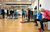 Kvinner trenar styrke og balanse i ein gymsal med manualar og matter.