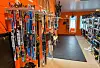 Rad med langrennsski og støvlar i lys sportsbutikk med oransje vegger.
