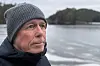 Mann i ullue og jakke ser utover ein kald, islagt fjord med skogkledde øyer.