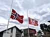 Norsk flagg og Sveio-flagget blafrar på halv stang framfor kommunehuset.