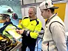 To personar studerer eit nettbrett ved ein motorsykkel på ei messe.