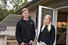 To personar står på ein terrasse framfor ei open dør til stova.