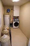 Lite vaskerom med kvit vaskemaskin, varmtvasstank og fleire korgar med skittentøy.