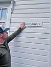 Mann peikar på eit skilt med teksten «Kittyhuset» på ein grå husvegg.