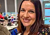 Elisabeth Stølås smiler i eit klasserom med pultar og elevar i bakgrunnen.
