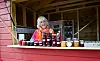 Astri Andersson står i ei raud salsbu med glas og flasker med frukt- og bærprodukt.