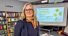 Gunnhild Staupe i eit bibliotek framfor ein skjerm med presentasjon om temakveldar.