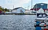 Utsyn over sjøen mellom Bakarøynå og Risøynå, med fritidsbåtar og industribygningar ved kaia.
