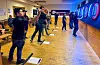 Dartspelarar kastar piler mot skiver i ein gamal skulebygning.