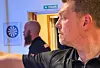 Bjarte Thorkildsen siktar mot ei dartskive i eit lokale, medan ein annan mann står i bakgrunnen.