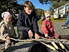 Tre barn sit rundt eit bål og held pinnar med mat over glørne.
