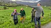 Fire personar frå Haugaland gjetarhundnemnd står på eit grønt jorde i fjellandskap.