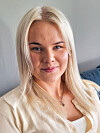 Nærportrett av ei blond kvinne i lys cardigan, fotografert innandørs.
