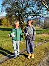 Erik Nappen og Felix Thomas står med bøsser på ein grusveg i eit grønt landskap.
