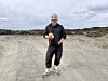 Person med vernehjelm står på ein grusveg i eit steinete landskap.