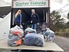 To personar ved ein lastebil med store plastsekker utanfor ein bygning.
