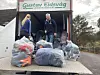 To personar ved ein lastebil med store plastsekker utanfor ein bygning.