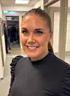 Caroline Stoknes frå Birkeland smiler til kameraet i ein korridor.